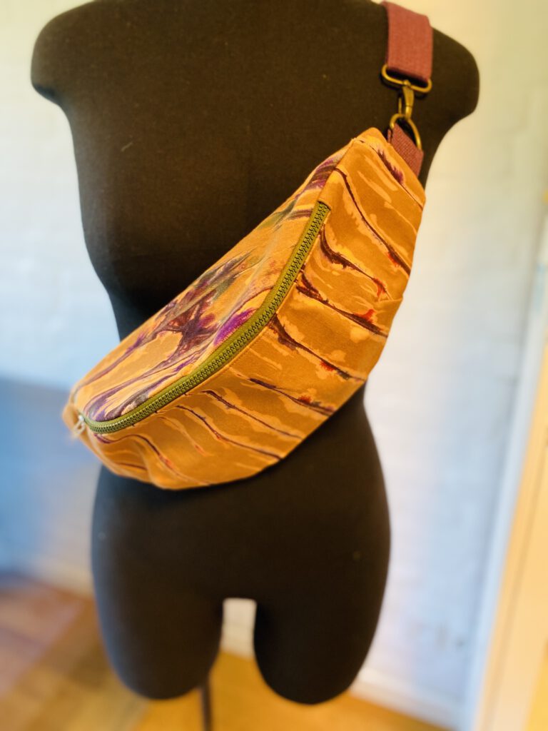 Belly Bag Kokocurry: violette Batikstreifen auf ockerfarbigem Hintergrund.