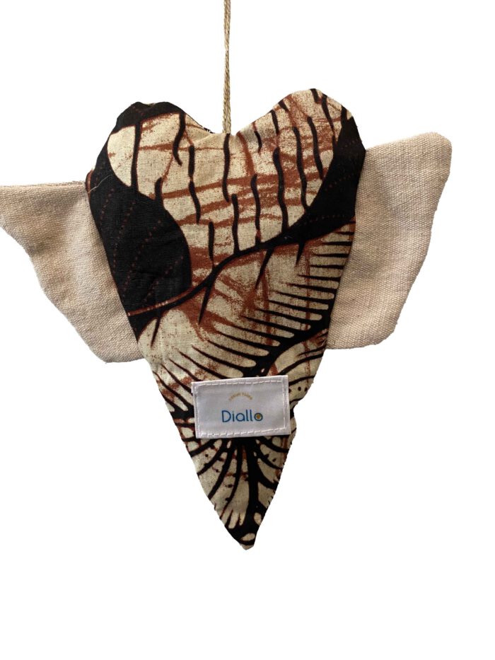 Herzförmiges Stoffobjekt mit grafischem Batikmuster in Braun, Beige und Schwarz, naturfarbene Flügel aus grobem Baumwollstoff, aufgehängt an einem golddurchwirkten Garnfaden.