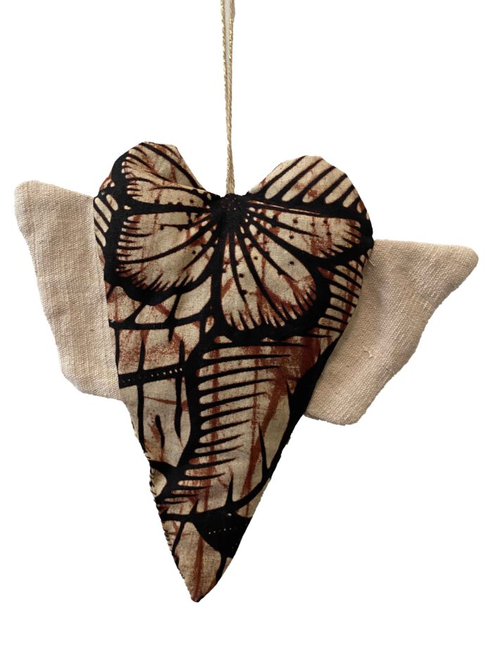 Herzförmiges Stoffobjekt mit grafischem Batikmuster in Braun, Beige und Schwarz, naturfarbene Flügel aus grobem Baumwollstoff, aufgehängt an einem golddurchwirkten Garnfaden.