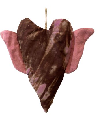Herzförmiges Stoffobjekt in erdigem Braun mit rosa Batikverläufen und Flügeln aus rosafarbenem Baumwollstoff, aufgehängt an einer naturfarbenen Kordel mit Goldakzent.