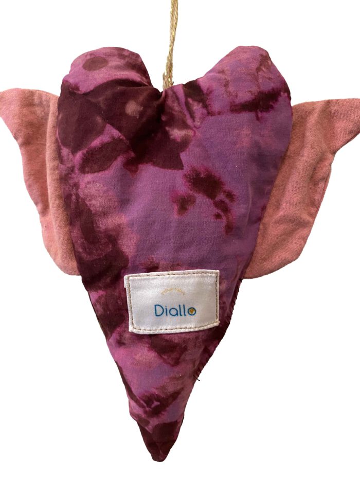 Handgemachtes Herz aus violett-pinkem Batikstoff mit weichrosa Flügeln, aufgehängt an einer naturfarbenen Kordel.