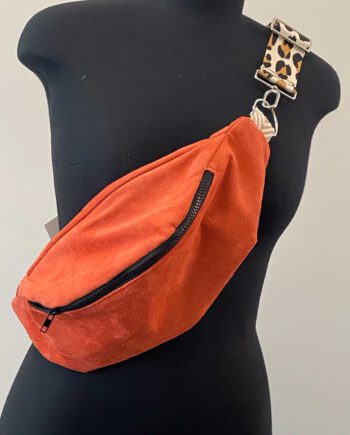 Flamingofarbene Bauchtasche (Belly Bag) aus Wildleder mit schwarzem Reißverschluss und abnehmbarem Schulterriemen in Leopardenmuster, inspiriert von afrikanischer Mode, präsentiert auf einer schwarzen Schneiderpuppe.
